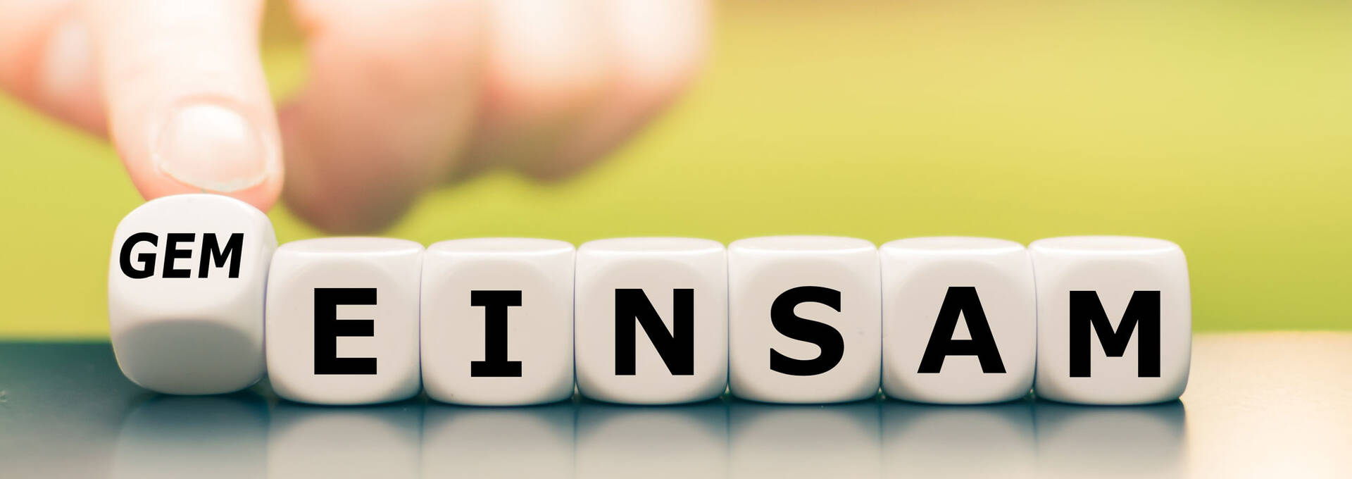 Symbolbild für Ökumene: Hand dreht einen Würfel und ändert das Wort "einsam" in "gemeinsam".