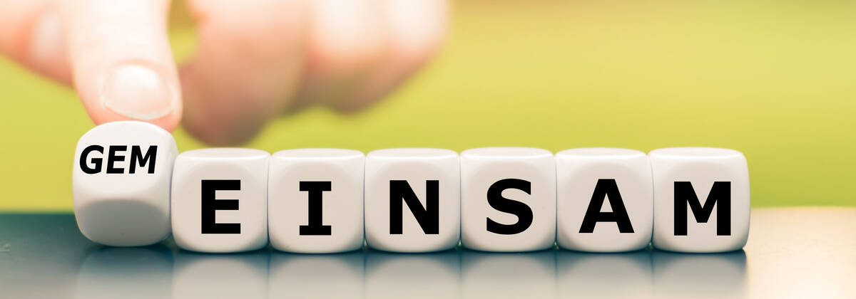 Link zur Seite Ökumene Symbolbild für Ökumene: Hand dreht einen Würfel und ändert das Wort "einsam" in "gemeinsam".