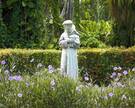 Eine Statue des hl. Franziskus von Assisi inmitten von Blumen und Bäumen