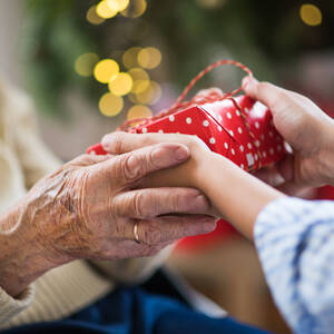 Close-up of hands of senior and young woman holding a present at Christmas.